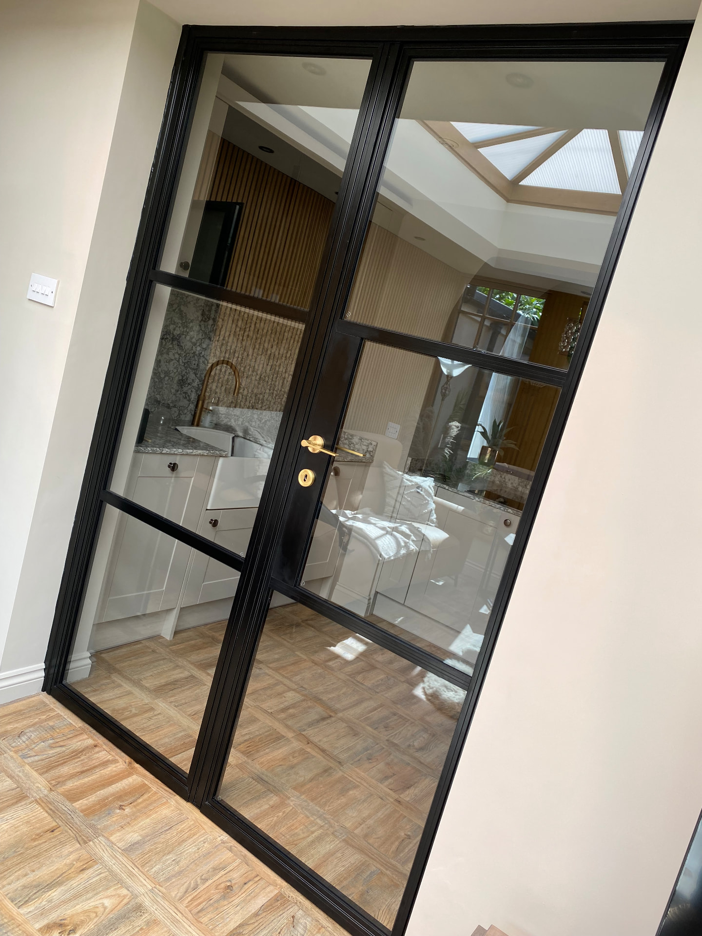 Black aluminium door and side screen between a kitchen and orangery
